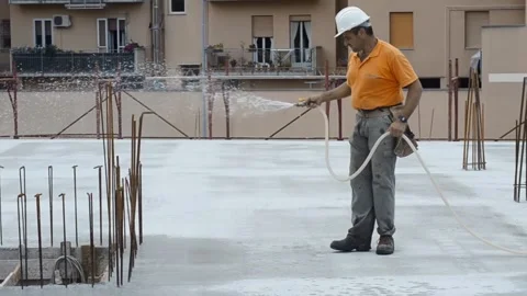 Construction worker watering fresh concrete slab using a hose. Stock-Footage 248428769