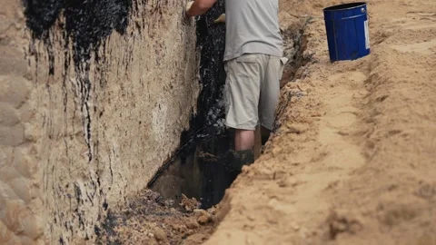Construction worker waterproofing building foundation with bitumen Stock Footage 341294554