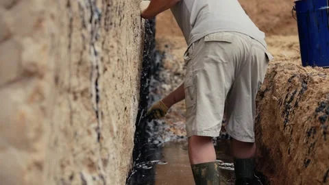 Construction worker waterproofing building foundation with bitumen Stock Footage 341294577