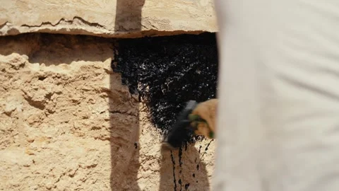 Construction worker waterproofing stone foundation with tar Stock Footage 341294420