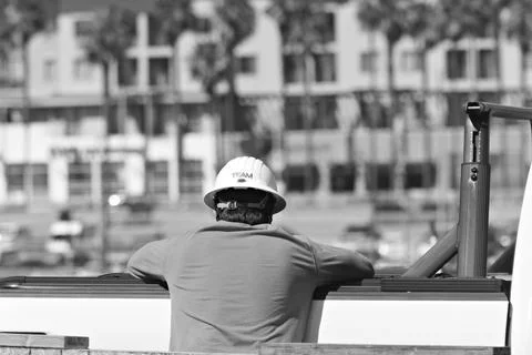 Construction worker wearing hard hat overlooks coastal development area Stock Photos