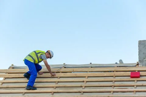 Construction worker wearing a hard hat and safety vest installing wooden sl.. Stock Photos