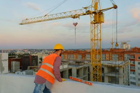 Construction worker wearing hardhat and safety vest leaning on concrete blo.. Stock Photos