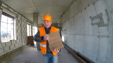 Construction worker wearing a helmet bricks in a new house under construction. Video stock 58297784