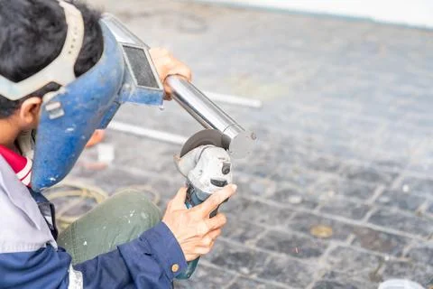 A construction worker wearing a protective face shield uses an angle grinde.. Foto stock