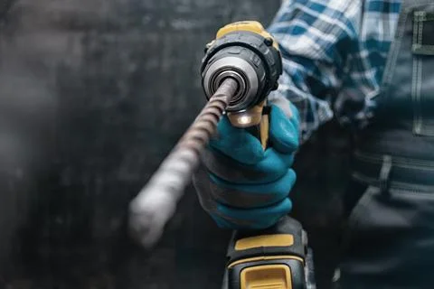 Construction worker wearing a protective glove holds a yellow cordless screwd Stock Photos