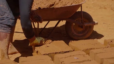 Construction worker wearing protective gloves stacking adobe bricks near Stock Footage 316760350