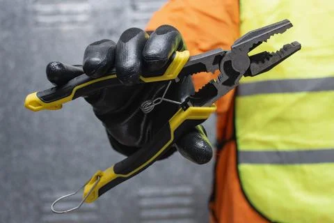Construction worker wearing protective gloves and safety vest holding metal.. Stock Photos