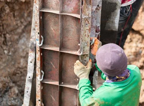 Construction worker wearing protective gloves and work clothing assembling .. Stock Photos