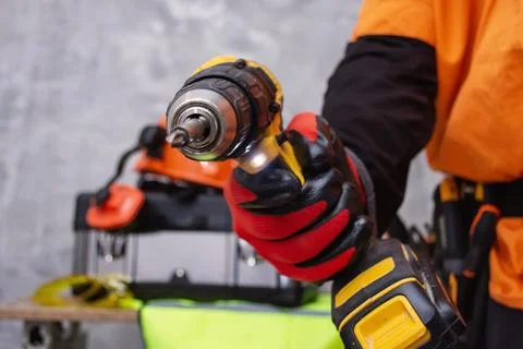 Construction worker wearing protective red work gloves and orange high-visibi Stock Photos