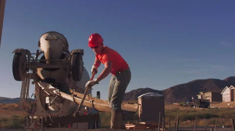 Construction worker wearing safety gear spreading concrete next to truck Stock Footage 55149080