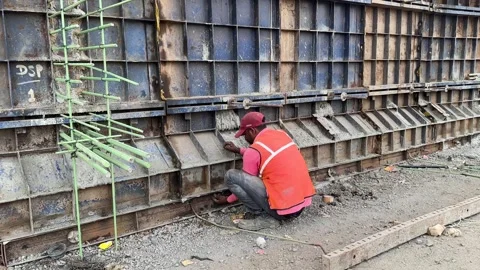 Construction worker welding the base of a large metal formwork structure Stock Footage 336942736