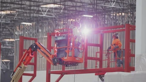Construction worker welding metal steel beams on a lift with sparks flying Stock Footage 257394180