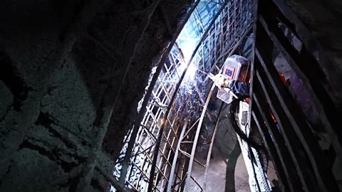 Construction worker welding rebar in a dark, confined tunnel structure Stock Footage 333007994