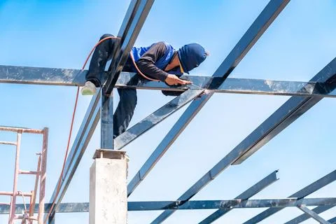 Construction worker welding on steel structure roof. Foto stock