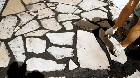 Construction worker in white gloves carefully placing natural flagstone til.. Stock Photos