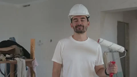 Construction worker in a white hard hat holding a paint roller Видео 282131606