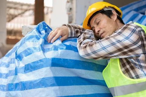 Construction worker with white safety helmet take a nap because so are tire.. Stock Photos