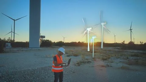 Construction worker at windmill park field planning new digital wind turbine. Foto stock