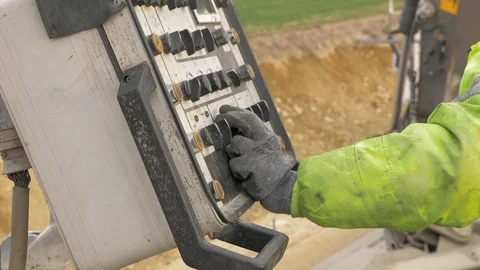 A construction worker in work clothes holds a hand on the knobs of control 動画素材 115907020