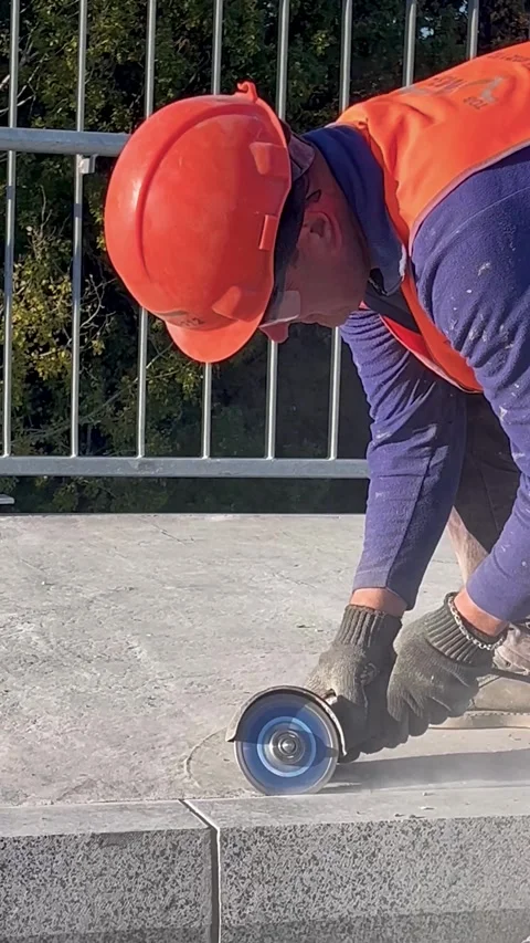 A construction worker in a work uniform and a helmet works as a grinder on a Stock Footage 290495670