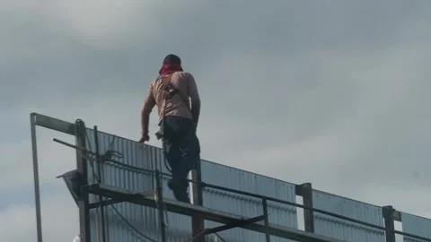Construction worker working at heights on scaffolding against cloudy sky Stock Footage 345100074