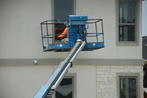 A construction worker working using boom lift vehicle on day in an apartment Stockfoto's