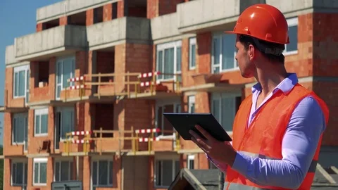 Construction worker works on the tablet in front of building site Stock-Footage 79050801