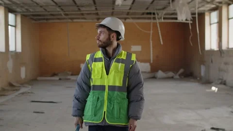A construction worker in a yellow vest and white helmet inspects the Stock Footage 237327411