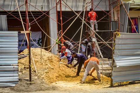 Construction workers in action at a busy urban building site with scaffoldi.. Stock Photos