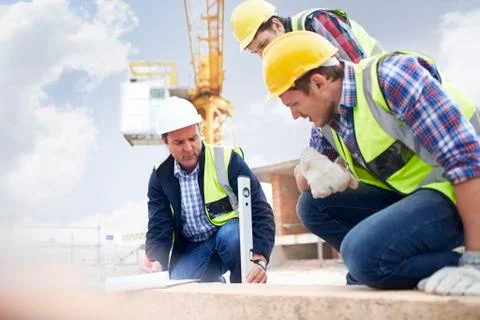 Construction workers and engineer using level tool at construction site Foto stock