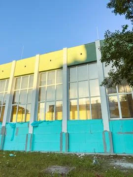 Construction workers apply new paint to a building's exterior with large wind Fotos Stock