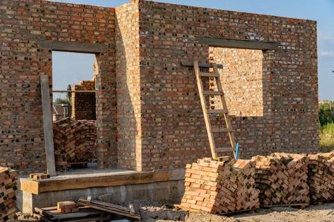 Construction workers are building a brick wall, which stands partially completed Stock Photos