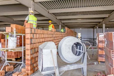 Construction workers are building dividing wall with red blocks and mortar Fotos de archivo