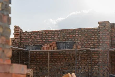 Construction workers are busy stacking bricks on site to build a sturdy wal.. Stockfoto's