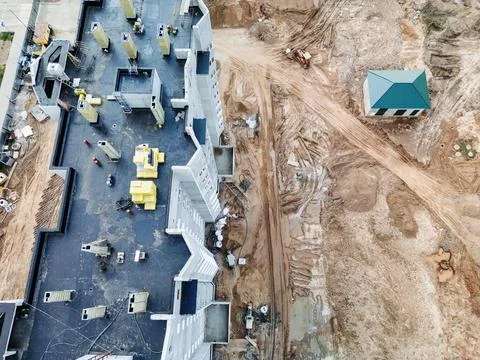 Construction workers are diligently building a structure surrounded by machin Stock Photos