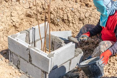 Construction workers are laying bricks around the pile. 스톡 사진