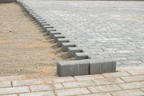 Construction workers are laying gray paving stones in a straight arrangement  Photos