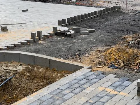 Construction workers are laying paving stones on a new driveway. Stock Photos