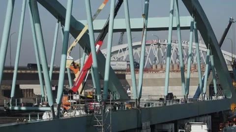 Construction workers are seen working on a partially built bridge while heavy Vídeo Stock 304112027