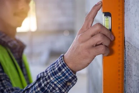 Construction workers are using water levels to measure the wall. Stock Photos