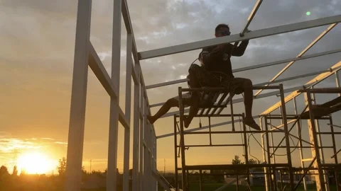Construction workers are welding a house frame in the beautiful sunset in the Stock Footage 321328460