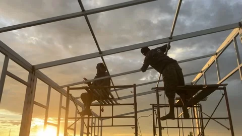 Construction workers are welding a house frame in the beautiful sunset in the Stock Footage 321328470