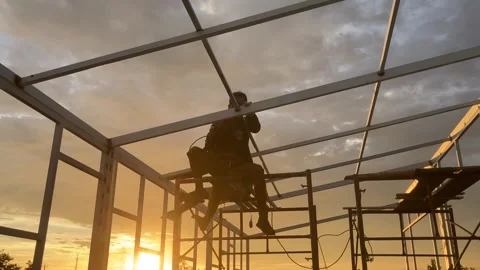 Construction workers are welding a house frame in the beautiful sunset in the Stock Footage 321328479
