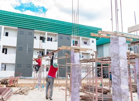 Construction workers assembling scaffolding and concrete columns at a build.. Foto stock