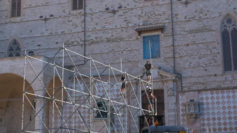 Construction workers assembling scaffolding on a historical building facade Stock Footage 323274409
