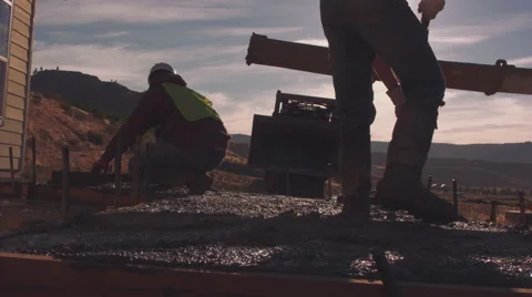 Construction workers backlit by the sun while spreading concrete Stock Footage 55149235