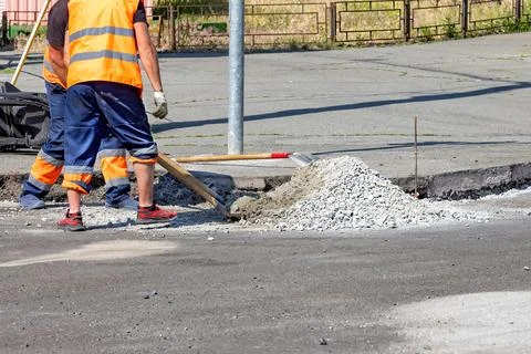 Construction workers in bright vests are busy repairing a city street, applyi Foto stock