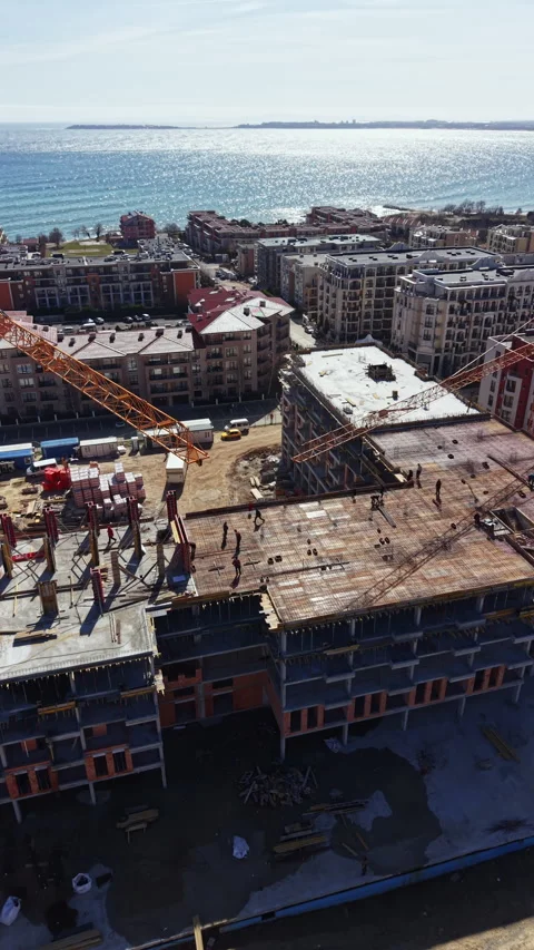 Construction workers build a high-rise building near the waterfront in bright Video stock 336549419