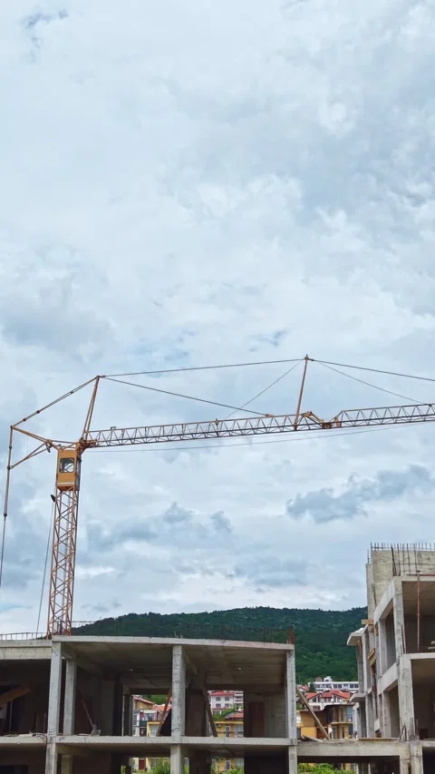 Construction workers build a multi-storey building with a crane under a cloudy Stock Footage 337906928